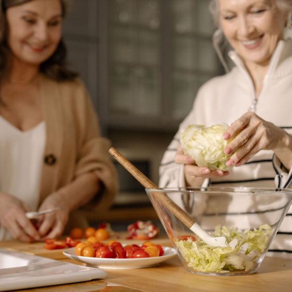 Zwei Frauen bereiten gemeinsam einen Salat zu.