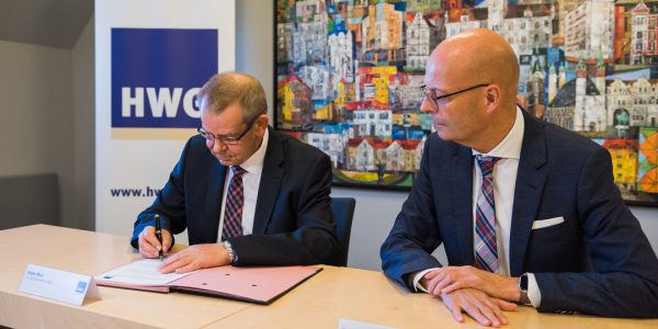 Der HWG-Geschäftsführer und der HWG-Aufsichtsratsvorsitzende unterschreiben die freiwillige Selbstverpflichtung