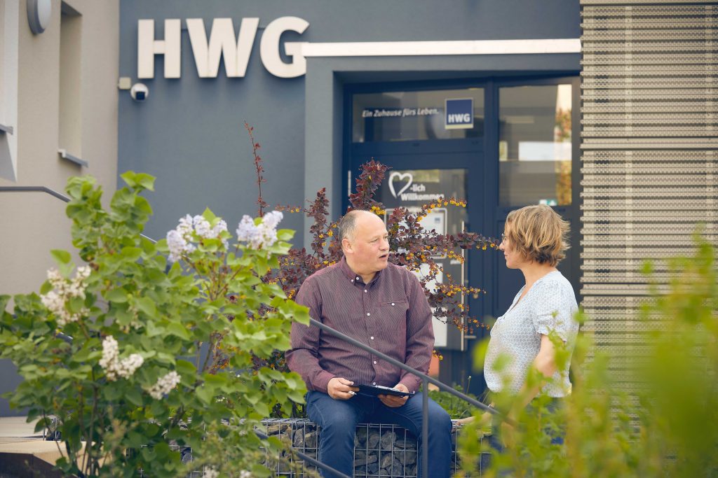 Mann und Frauen unterhalten sich vor HWG-Mieterladen